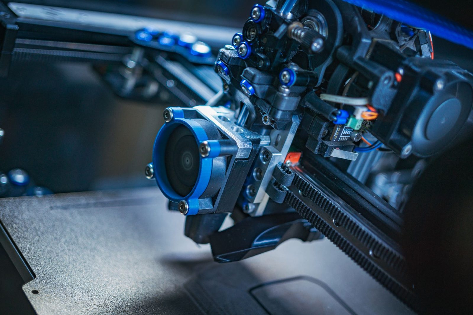 Cabeçote de impressora 3D em close, com ventoinha, correia dentada, parafusos e cabos (foto ilustrativa, não é o ACE Pro): no ACE, filamento preso na engrenagem exige abrir a tampa e girar com a mão