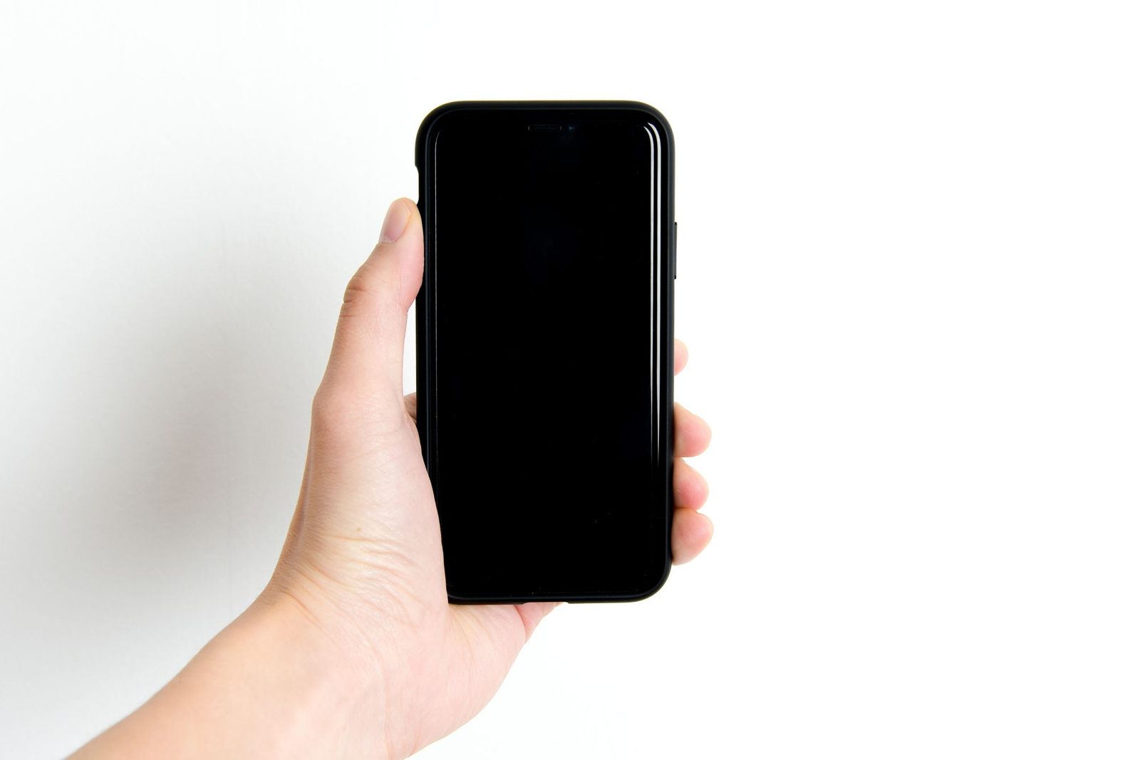 Mão segurando um celular com a tela totalmente preta, contra um fundo branco