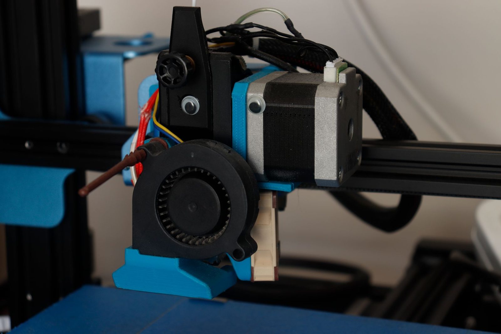 Cabeça de impressão de uma impressora 3D FDM genérica em close, com fios vermelhos e fios finos saindo do hotend ao lado da ventoinha, como os cabos de resistência e termistor que se desconectam na placa adaptadora da Kobra 3 V2