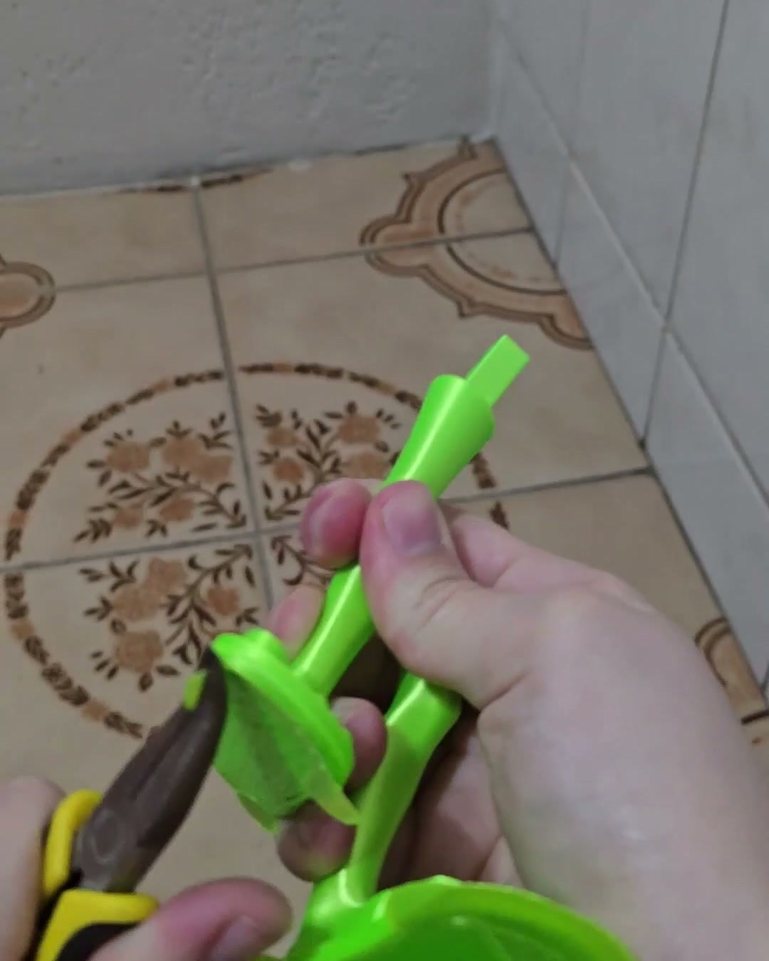 Peças do alien neon recém-impressas com suporte, sendo limpas com alicate de corte