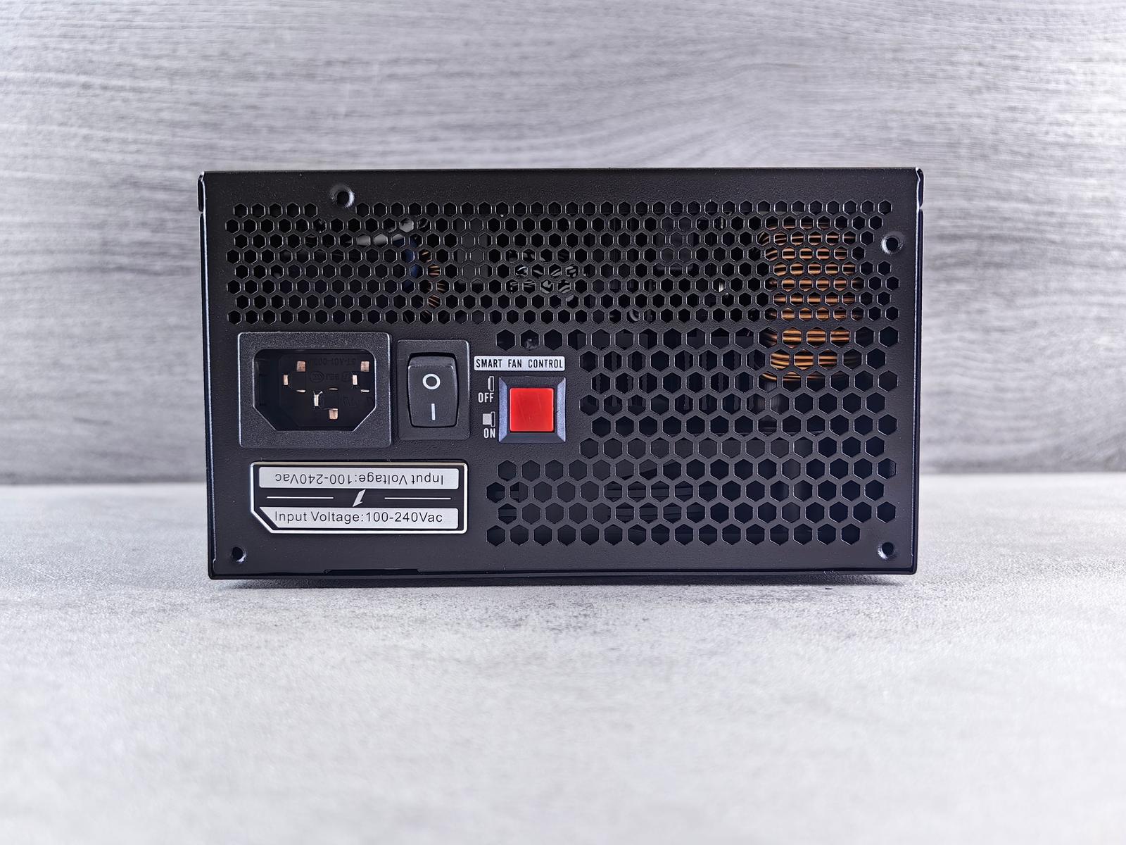 Traseira de uma fonte de computador com a entrada do cabo, o botão liga e desliga e a etiqueta "Input Voltage: 100-240Vac"