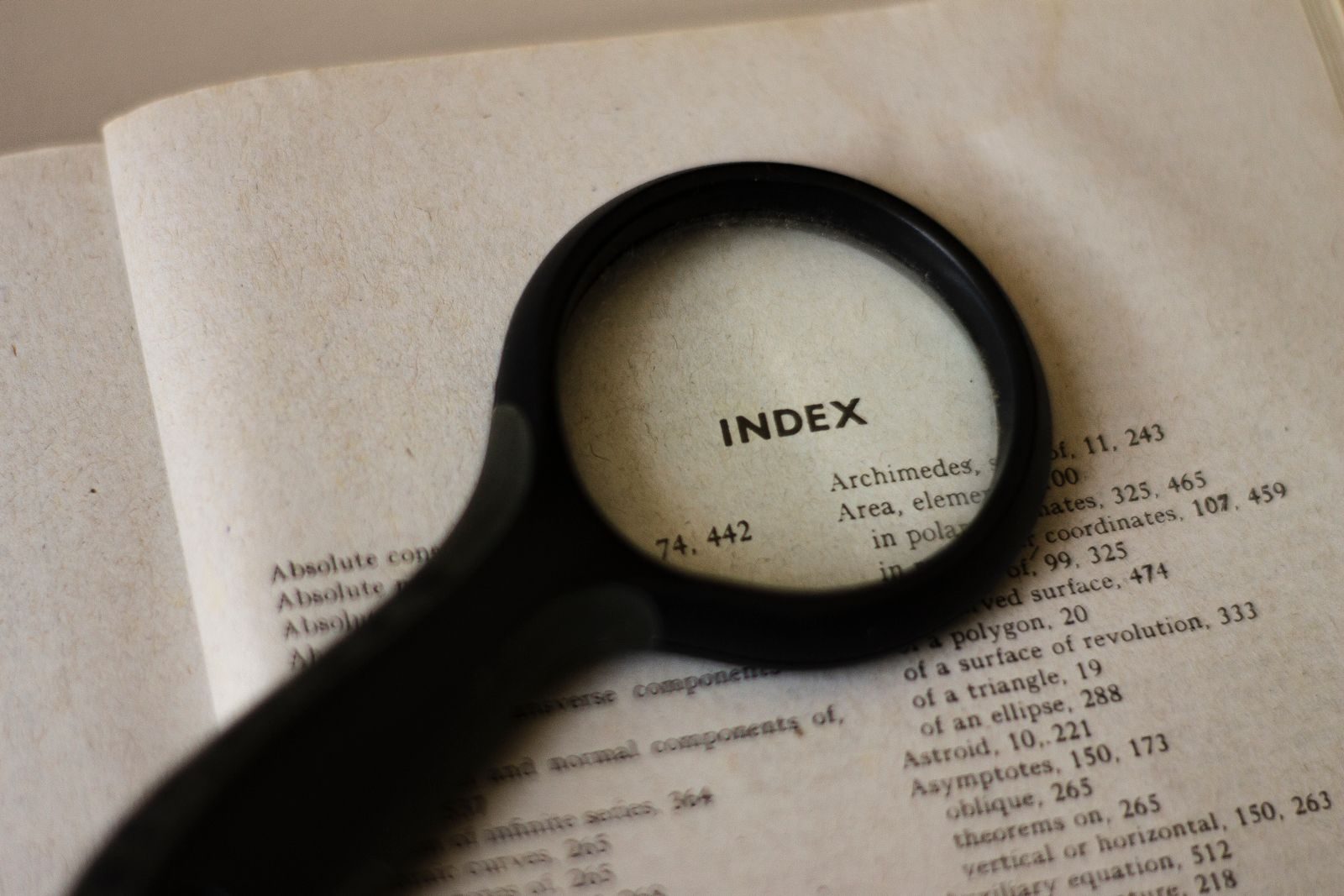 Lupa sobre a página de índice de um livro aberto, ampliando a palavra INDEX