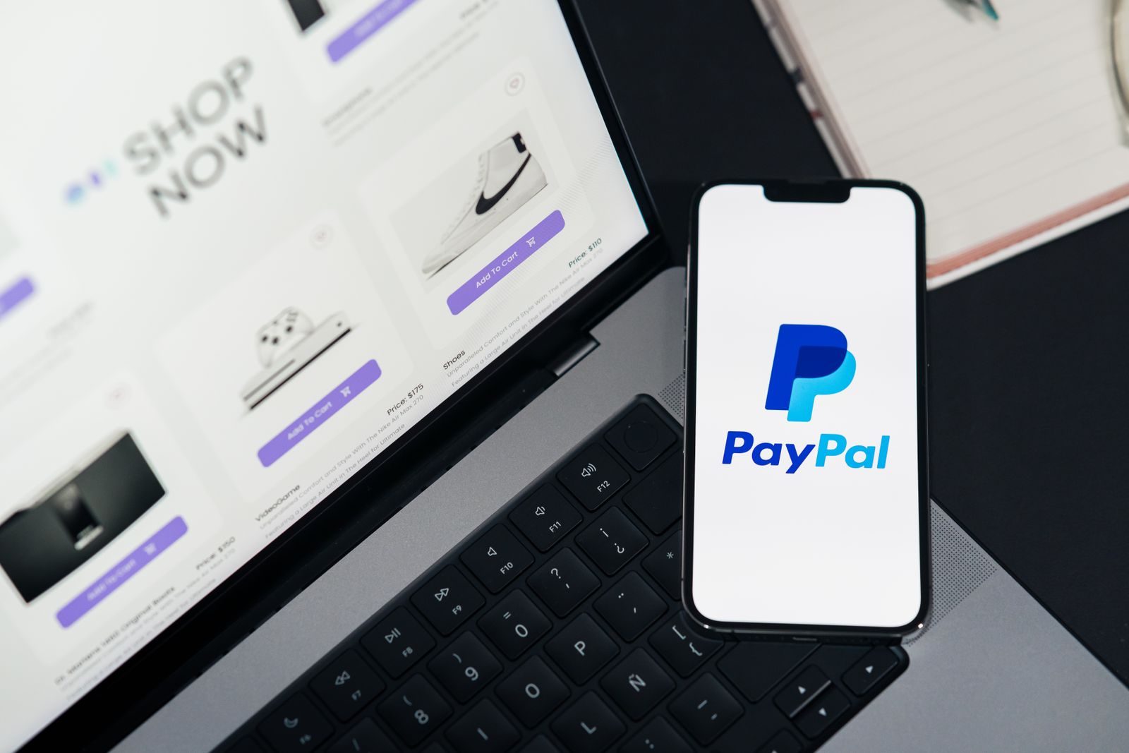 Celular com o logo do PayPal na tela, apoiado no teclado de um notebook aberto numa loja online